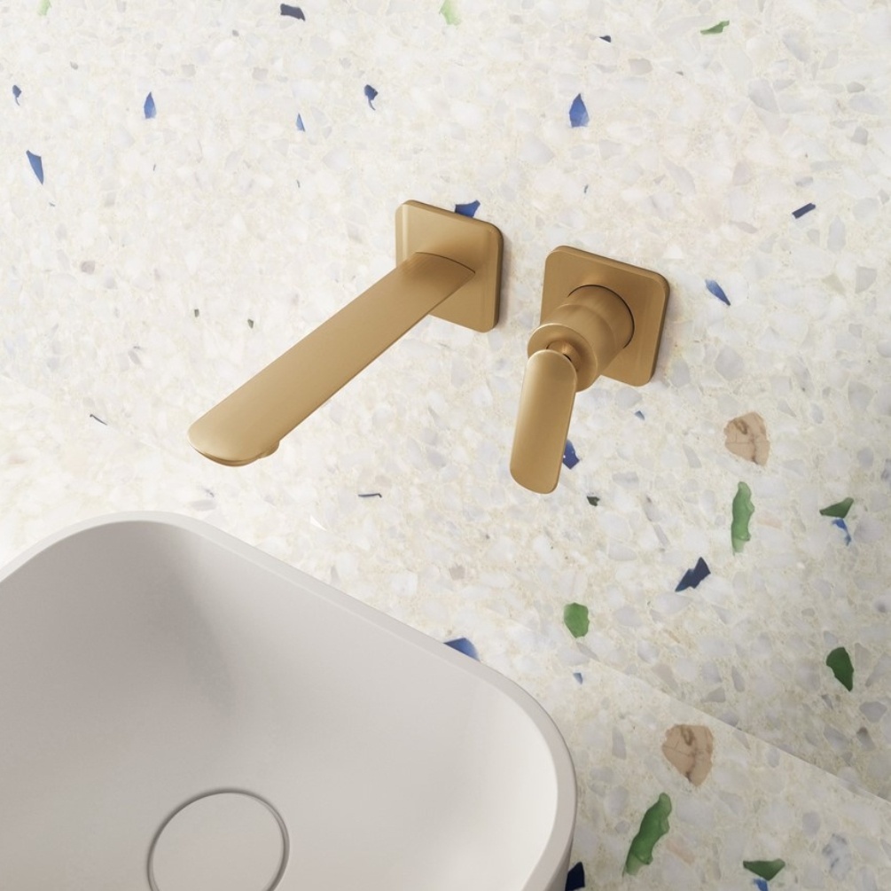 Lifestyle image of the Crosswater Huck Brushed Brass Wall Mounted Basin Mixer installed above a white countertop basin